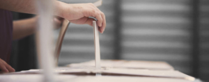 Hand of a person casting a ballot at a polling station during voting.